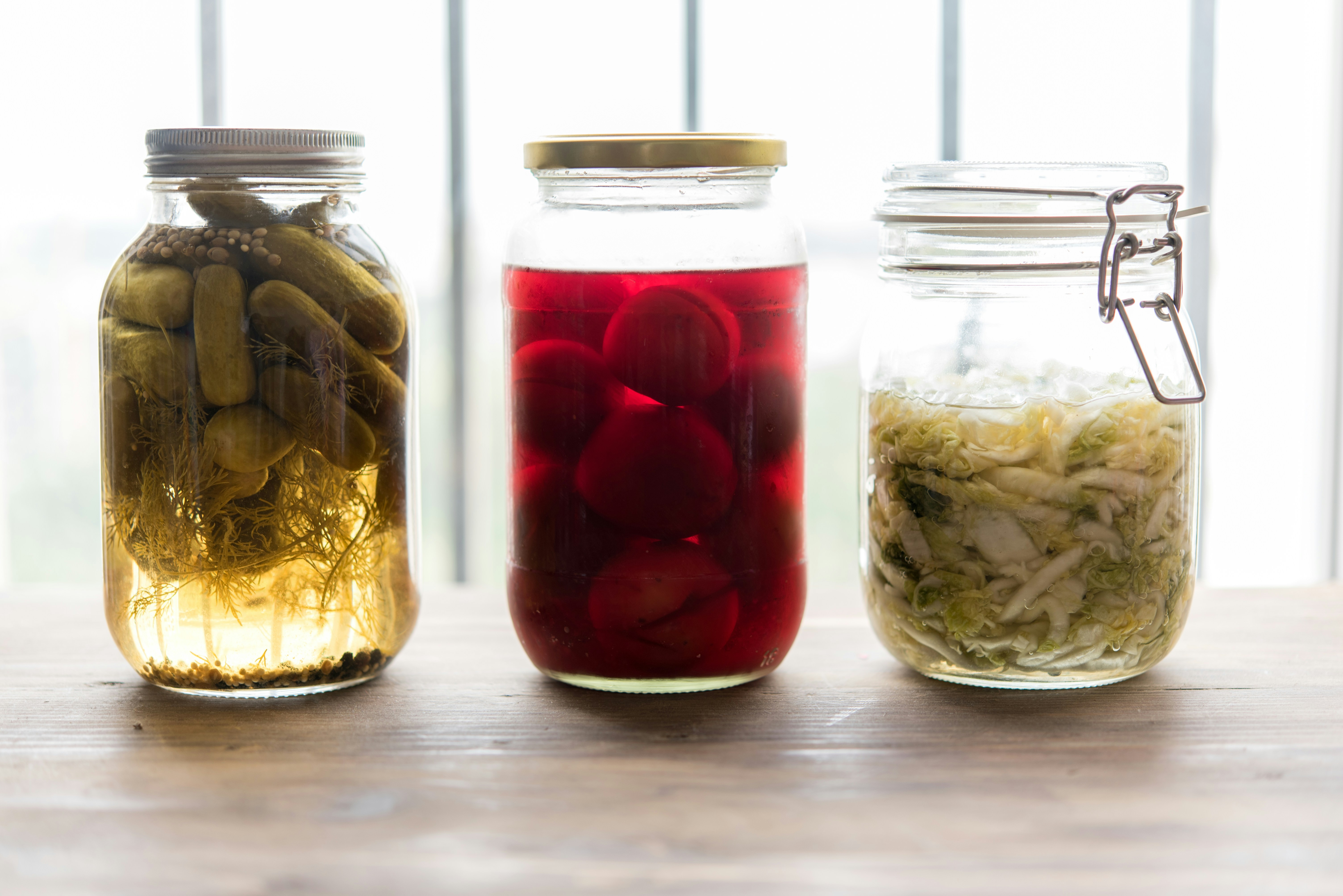 Photo de trois bocaux contenant des préparations lacto-fermentées. Photo de Anshu A sur Unsplash